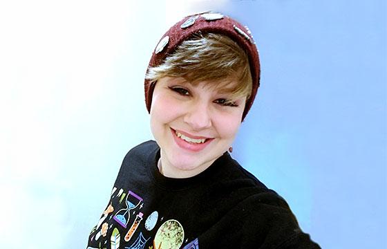 smiling Saymia wearing hat blue background